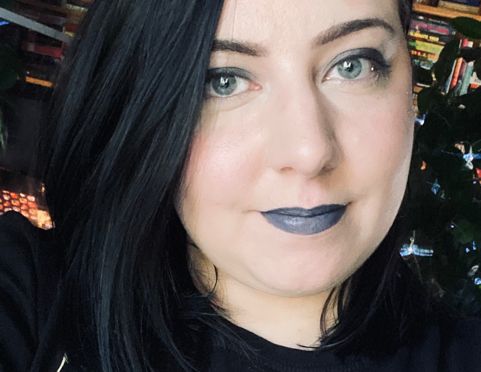 A selfie of me. I have jet black hair that falls to my shoulders and I am wearing smoky eyeshadow and gray lipstick.