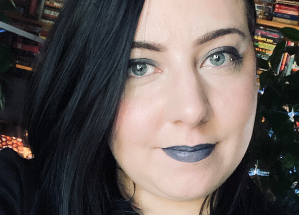 A selfie of me. I have jet black hair that falls to my shoulders and I am wearing smoky eyeshadow and gray lipstick.